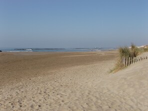 En sandstrand med ett trästaket och en klar himmel.