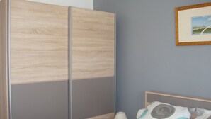 Makuuhuone, jossa on sänky, yöpöytä, lamppu ja vaatekaappi.