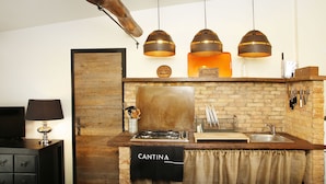 Une cuisine avec un mur de fond en briques, un plan de travail en bois et des luminaires suspendus.