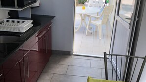 Kompakti keittiö, jossa on mikroaaltouuni, pesuallas sekä ruokailutila pöytineen ja tuoleineen.