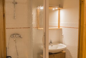 Une salle de bain avec une douche à parois de verre, un lavabo et un meuble en bois.
