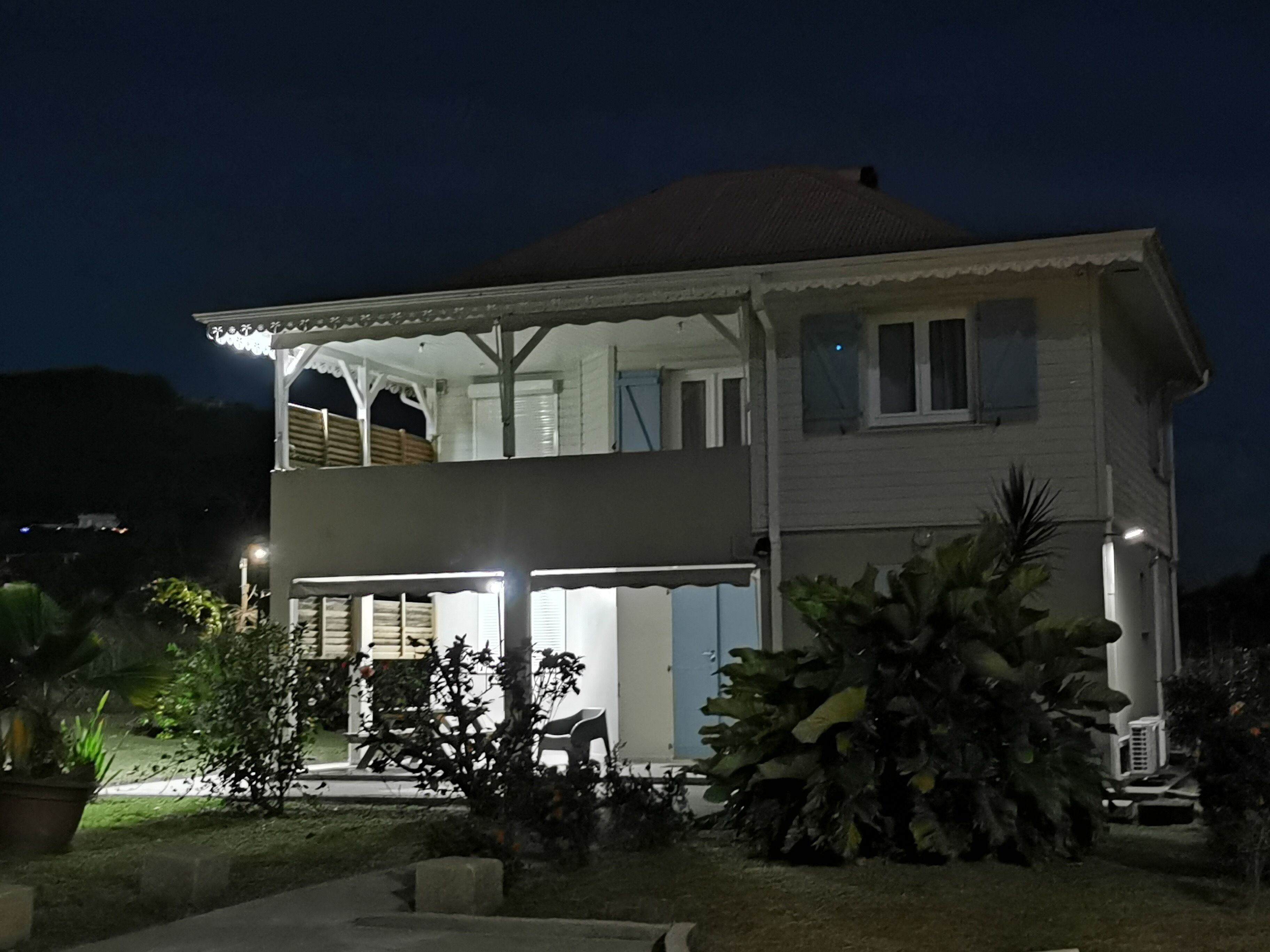 A two-story house with a balcony, a covered porch, and a large tree in the front yard.