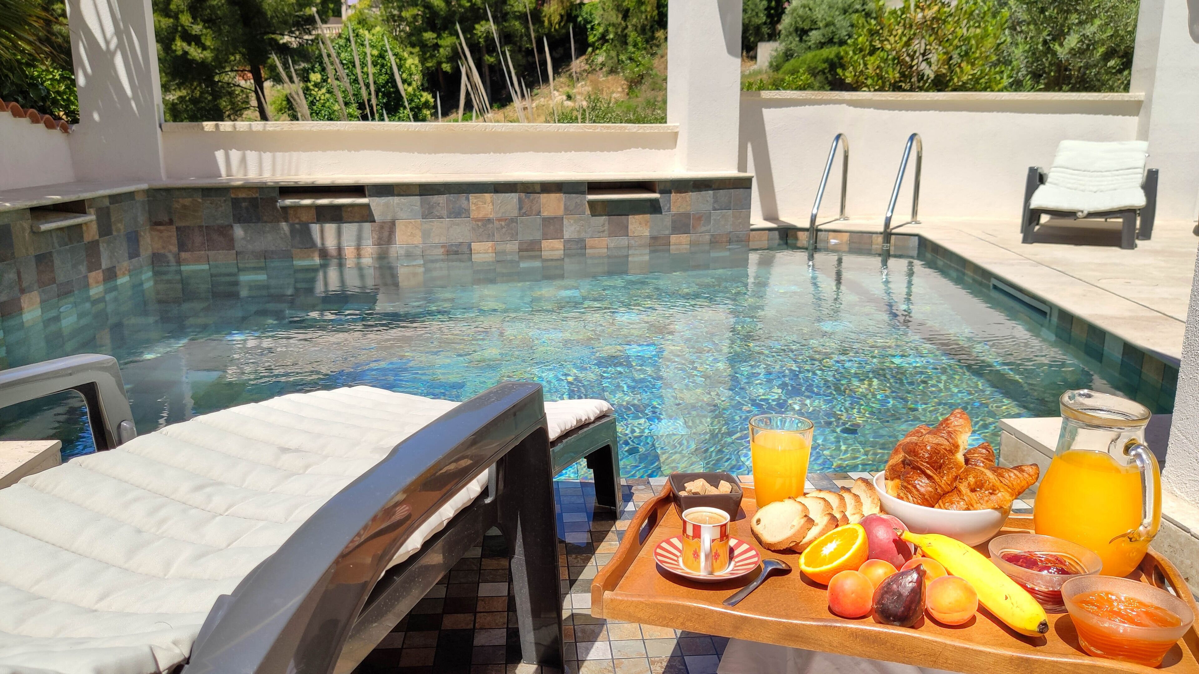 A poolside breakfast tray with fruits, bread, and beverages.