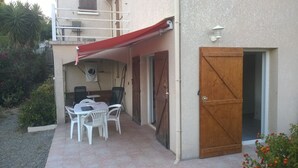 A patio with a table and chairs, a wooden door, and a red awning. - AFA villa floor 15 km from Ajaccio (Afa)