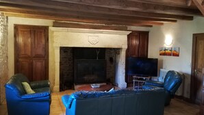Ein gemütliches Wohnzimmer mit Kamin, Ledersofas, einem Fernseher und Holzschränken.