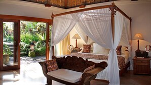 A four-poster canopy bed with a view of tropical plants through the glass door. - Villa Ria Sayan Ubud (Ubud)