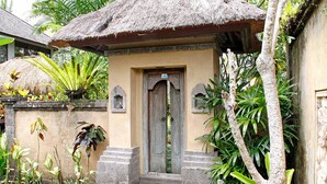 Une maison traditionnelle en bois, avec un toit de chaume, une entrée en pierre et un petit porche.