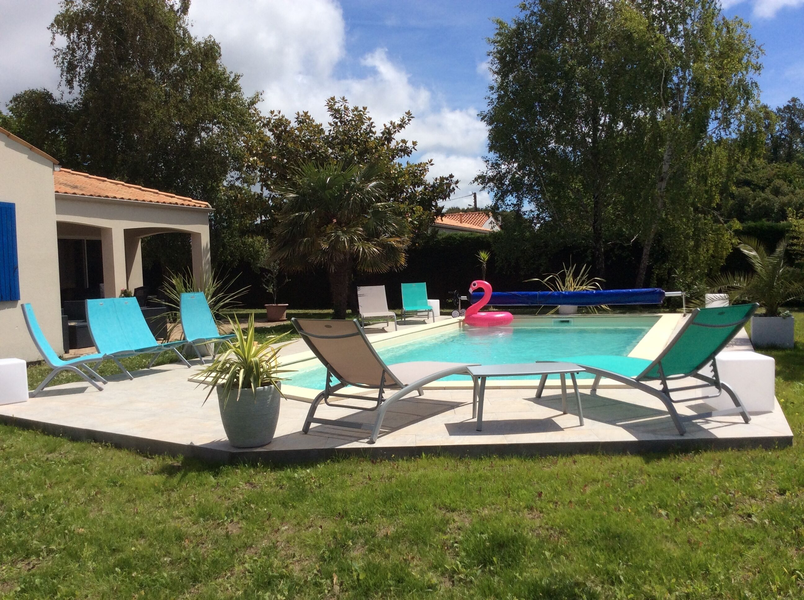 A swimming pool with lounge chairs and a pink flamingo float.