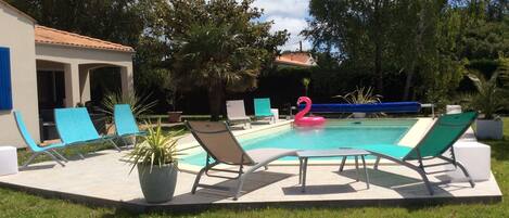 A swimming pool with lounge chairs and a pink flamingo float.