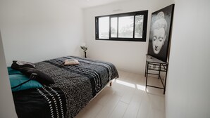 Une chambre à coucher avec un lit, un bureau, une fenêtre et un tableau accroché au mur.