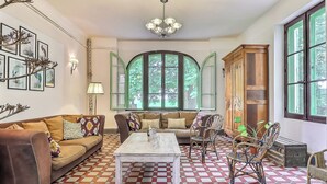 A cozy living room with a checkered floor, a sofa, a coffee table, and a window with green shutters. - 🌿Superb Maison de Maître in Provence with XXL infinity pool and bicycles🌿 (Beaucaire)