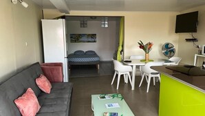 A compact living space with a sofa, a dining table with chairs, a kitchen area, and a TV mounted on the wall. - Pleasant apartment. on the ground floor 5 mins walk from the beach, Sainte Anne (SAINTE ANNE)