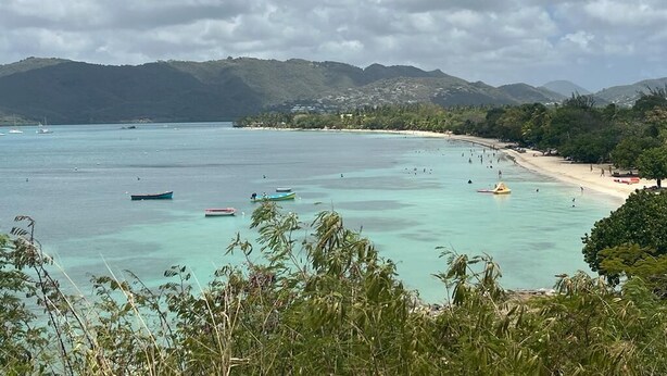 A coastal view with clear turquoise waters, boats, and a sandy beach with a backdrop of hills and a partly cloudy sky. - Pleasant apartment. on the ground floor 5 mins walk from the beach, Sainte Anne (SAINTE ANNE)