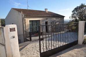 A house with a tiled roof, a metal gate, and a number 21 sign on the wall.