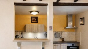 Una cocina con gabinetes de madera, un horno de acero inoxidable y dos taburetes de bar.
