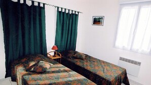 A room with two single beds, a chair, a table, a picture on the wall, and a window with curtains. - BEAUTIFUL APARTMENT FOR 4 PEOPLE WELL (Propriano)