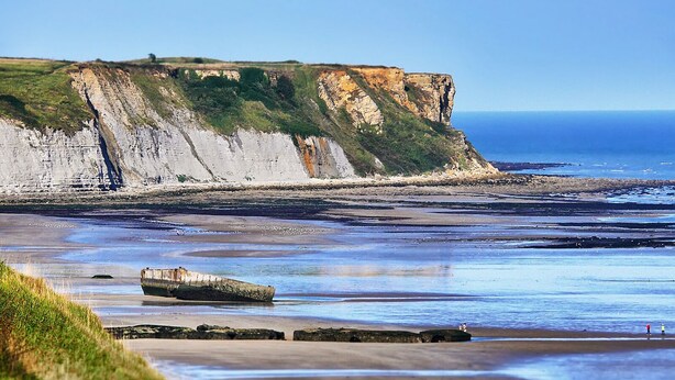 A coastal landscape with cliffs, a beach, and a large rock structure. - Beautiful house with sea view and fireplace (Ver-sur-Mer)