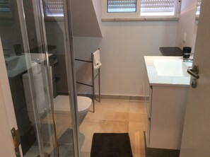 A small bathroom with a glass shower enclosure, a white sink, and a toilet.