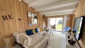 A cozy room with a wooden interior, a large bed with striped bedding, a small table with a vase, and a chair.