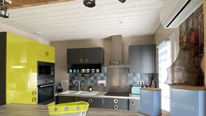 A modern kitchen with a yellow accent wall, stainless steel appliances, and a unique island with a star-patterned bag.