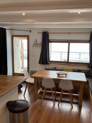 Un comedor acogedor con una mesa y sillas de madera, un banco y vistas al exterior.