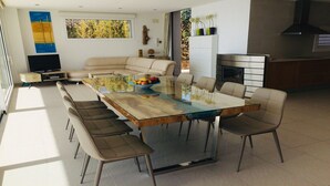 A modern living room with a glass-top dining table, beige sofas, and a fireplace. - Architect- villa, heated infinity pool, stunning 360° sea/mountain view, WIFI (Tamariu)