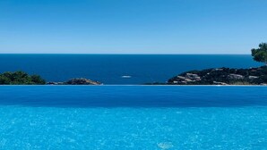 A clear blue pool with a view of the ocean and rocky terrain. - Architect- villa, heated infinity pool, stunning 360° sea/mountain view, WIFI (Tamariu)