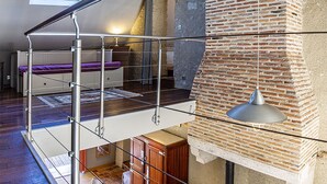 Een slaapkamer in een loft met een entresol, een metselwerk openhaard en een dakraam.