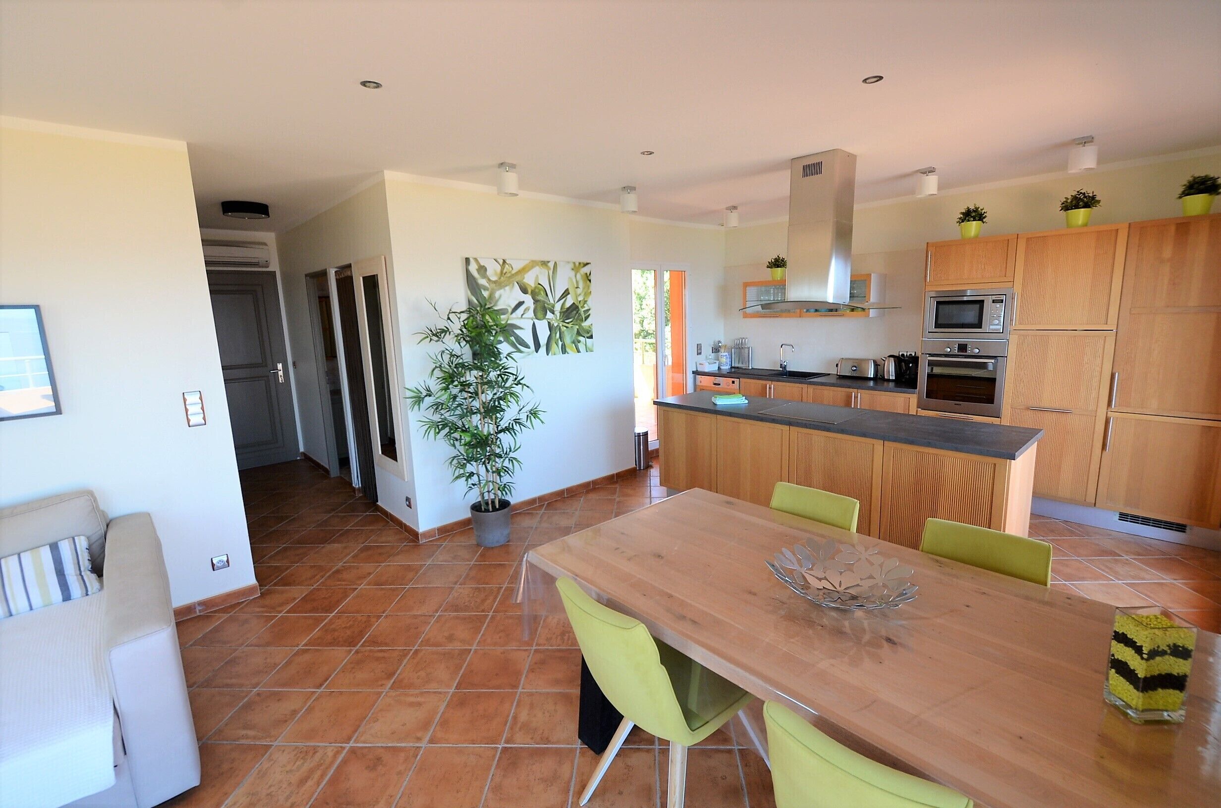 Une cuisine moderne avec des meubles en bois, un îlot central et un coin repas comprenant une table et des chaises en bois.