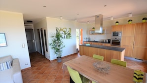 A modern kitchen with wooden cabinets, a central island, and a dining area with a wooden table and chairs.