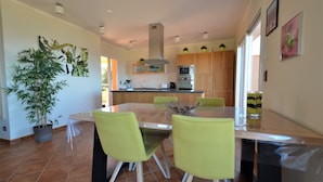 A modern kitchen with a central island, wooden cabinets, and a large potted plant.