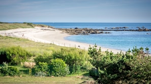 A beach with a sandy shore, rocky outcrops, and a clear blue sea.