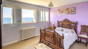 A bedroom with a large window, a bed, a chair, and a radiator. - house direct access to the beach, quiet location exceptional view from the terrace  (Trégunc)