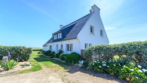 A white house with a steeply pitched roof, surrounded by well-maintained hedges and a gravel driveway. - house direct access to the beach, quiet location exceptional view from the terrace  (Trégunc)