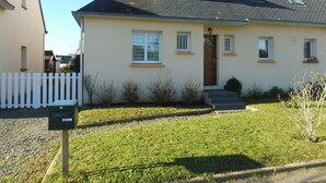 Une maison à deux étages avec une porte d’entrée, des fenêtres et un petit porche.