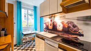 Eine moderne Küche mit Schachbrettboden, einem Fenster mit blauen Vorhängen und einem wandmontierten Backofen.