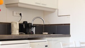Una cocina equipada con cafetera, lavaplatos y lavamanos.
