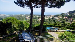 Un patio con mobiliario exterior, una piscina y vistas a un pueblo costero.