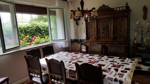 Un comedor con una mesa cubierta por un mantel con motivos de chocolate, rodeada de sillas de madera.