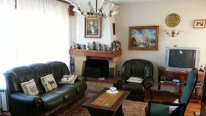 Una sala de estar con chimenea, sofás de cuero, una mesa de centro y un televisor.