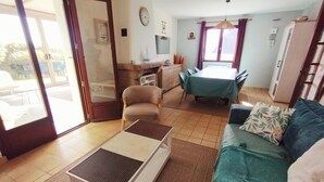 A living room with a sofa, a coffee table, and a dining area with a table and chairs. - South Brittany House Sea View in Port-louis 8 -10 people (Port-Louis)