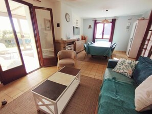 A living room with a sofa, a coffee table, and a dining area with a table and chairs. - South Brittany House Sea View in Port-louis 8 -10 people (Port-Louis)
