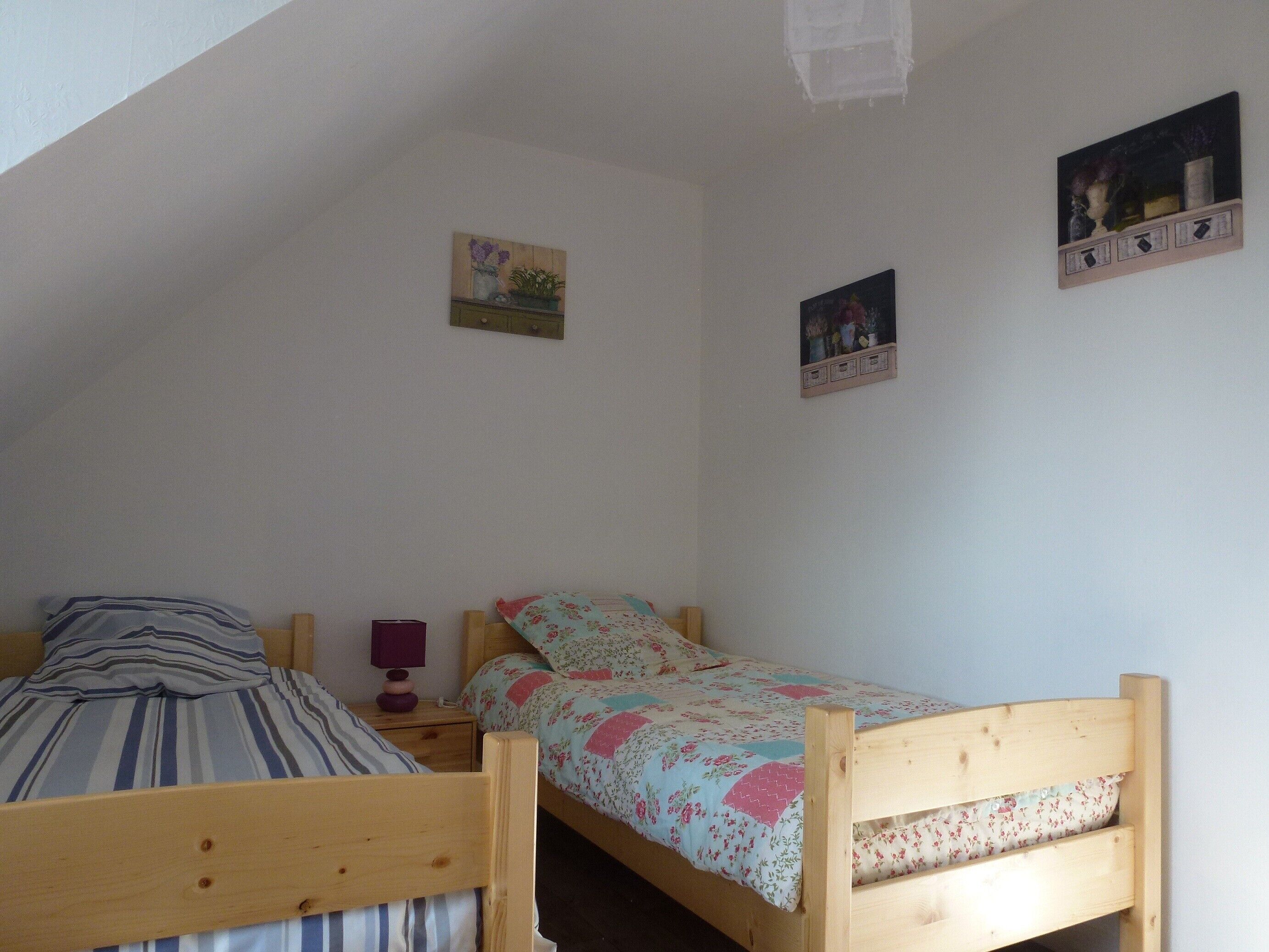 A bedroom with two wooden beds, a nightstand, and wall-mounted shelves with decorative items.