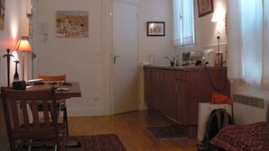 Un espace de vie compact comprenant un coin repas, une kitchenette et une petite chambre.