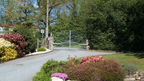 A gated entrance with a stone wall and flower beds. - Quiet, restful house with private pool in a tourist area (Bout-Du-Pont-De-Larn)