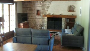 A living room with a stone fireplace, a television, and two sofas. - Quiet, restful house with private pool in a tourist area (Bout-Du-Pont-De-Larn)