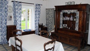 A dining room with a table, chairs, a wooden cabinet, and a window with curtains. - Family house near Morlaix, enjoy the countryside and the sea (Plouigneau)