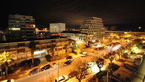 A nighttime cityscape with modern buildings, a parking area, and a street with cars. - 2-3 pers air-conditioned studio with harbor and sea view - Grande Motte (La Grande-Motte)
