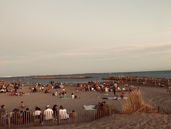 A crowded beach with people sitting and walking.