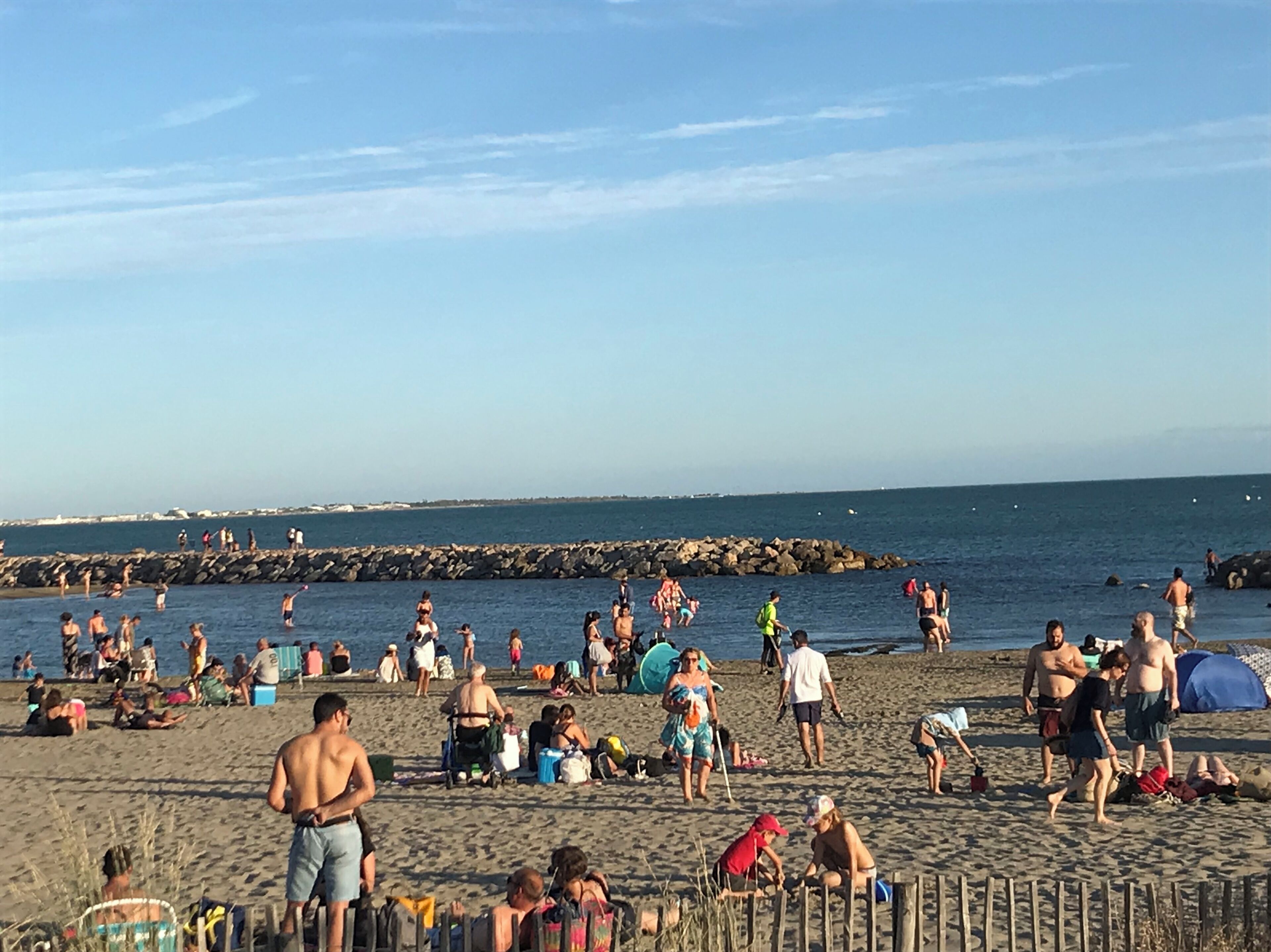 A crowded beach with people sunbathing and swimming.